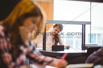 Focused student sitting next to the window taking notes