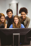 Smiling students using computer together looking at camera