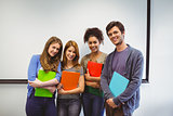 Students standing and smiling at camera holding notepads