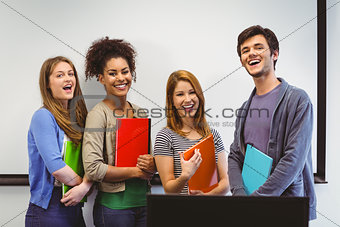 Students standing and smiling at camera holding notepads