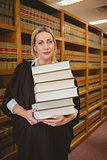 Lawyer holding heavy pile of books standing