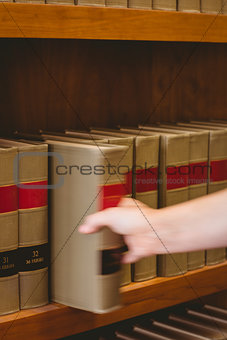 Hand taking a book from bookshelf