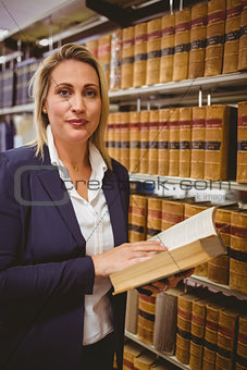 Woman reading a book from shelf standing