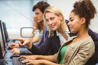 Attractive teacher talking to her student in computer class