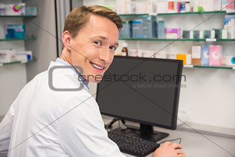 Happy pharmacist using the computer