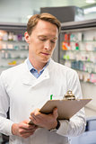 Focused pharmacist writing on clipboard