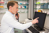 Serious pharmacist on the phone using computer