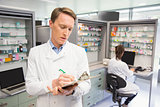 Focused pharmacist writing on clipboard