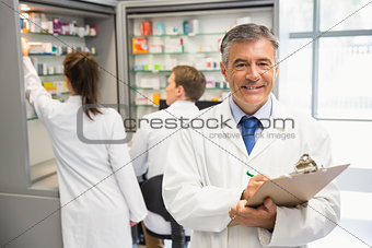 Senior pharmacist writing on clipboard