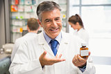 Senior pharmacist showing medicine jar