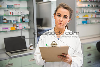 Junior pharmacist writing on clipboard