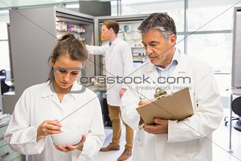 Junior pharmacist mixing a medicine being supervised