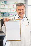 Happy pharmacist showing page on clipboard