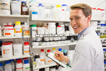 Handsome pharmacist writing on clipboard
