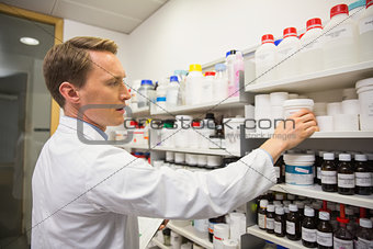 Handsome pharmacist taking medicine from shelf