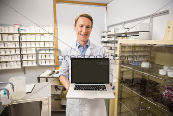 Happy pharmacist showing laptop screen