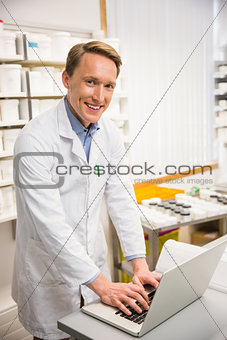 Happy pharmacist using his laptop