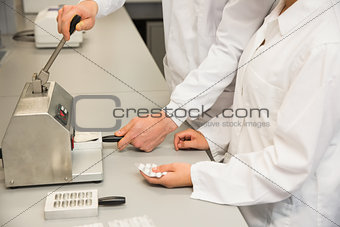 Team of pharmacists using press to make pills