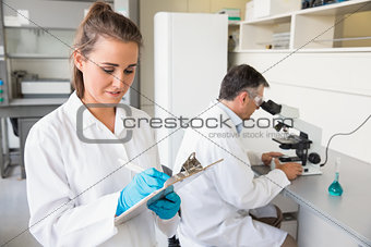 Young scientist writing on clipboard
