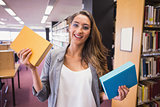 Pretty student smiling at camera in library