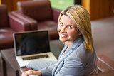 Blonde businesswoman smiling using laptop