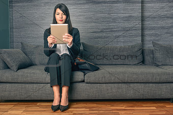 Businesswoman sitting reading a tablet-pc