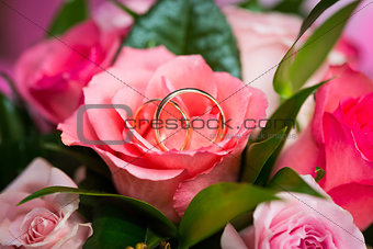 Two wedding rings on rose in bridal bouquet 