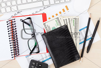 Office desk with reports, blank notepad and money cash