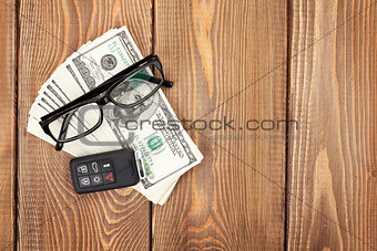 Money cash, glasses and car remote key on wooden table