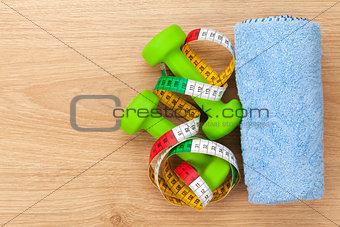 Dumbells and tape measure over wooden table with copy space