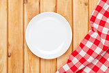 Empty plate and towel over wooden table background