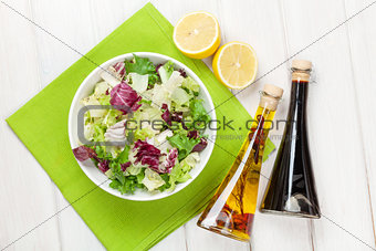 Fresh healthy salad and condiments over white wooden table