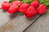 Fresh red tulips bouquet over wooden table background