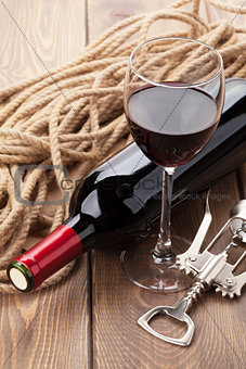 Glass of red wine, bottle and corkscrew