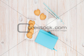 Cup of milk, heart shaped cookies and notepad