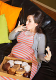 Donut Eating Pregnant Woman on Sofa