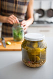 Closeup on jar of marinated cucumbers on table and housewife pic