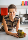 Portrait of happy young housewife with jar of pickled cucumbers