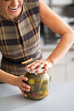 Closeup on young housewife opening jar of pickled cucumbers