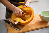 Closeup on young housewife removing filling from pumpkin