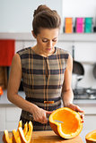 Young housewife cutting pumpkin in kitchen