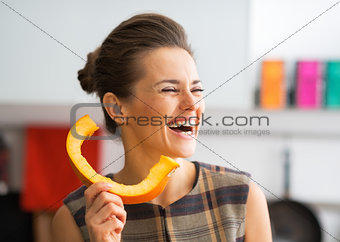Smiling young housewife using pumpkin slice as phone handset