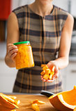 Closeup on young housewife showing jar of pickled pumpkin and pu