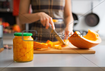 Closeup on jar of pickled pumpkin and young housewife cutting in