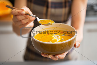 Young woman showing pumpkin soup