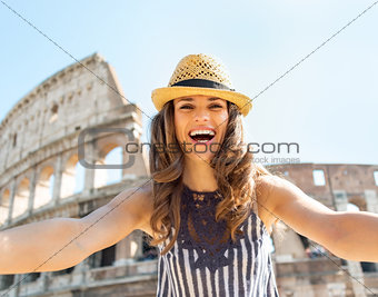 Happy young woman making selfie in front of colosseum in rome, i