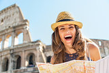Portrait of happy young woman with map in front of colosseum in 