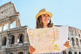 Happy young woman with map in front of colosseum in rome, italy