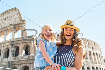 Portrait of happy mother and baby girl in front of colosseum in 