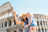 Happy mother and baby girl sightseeing near colosseum in rome, i